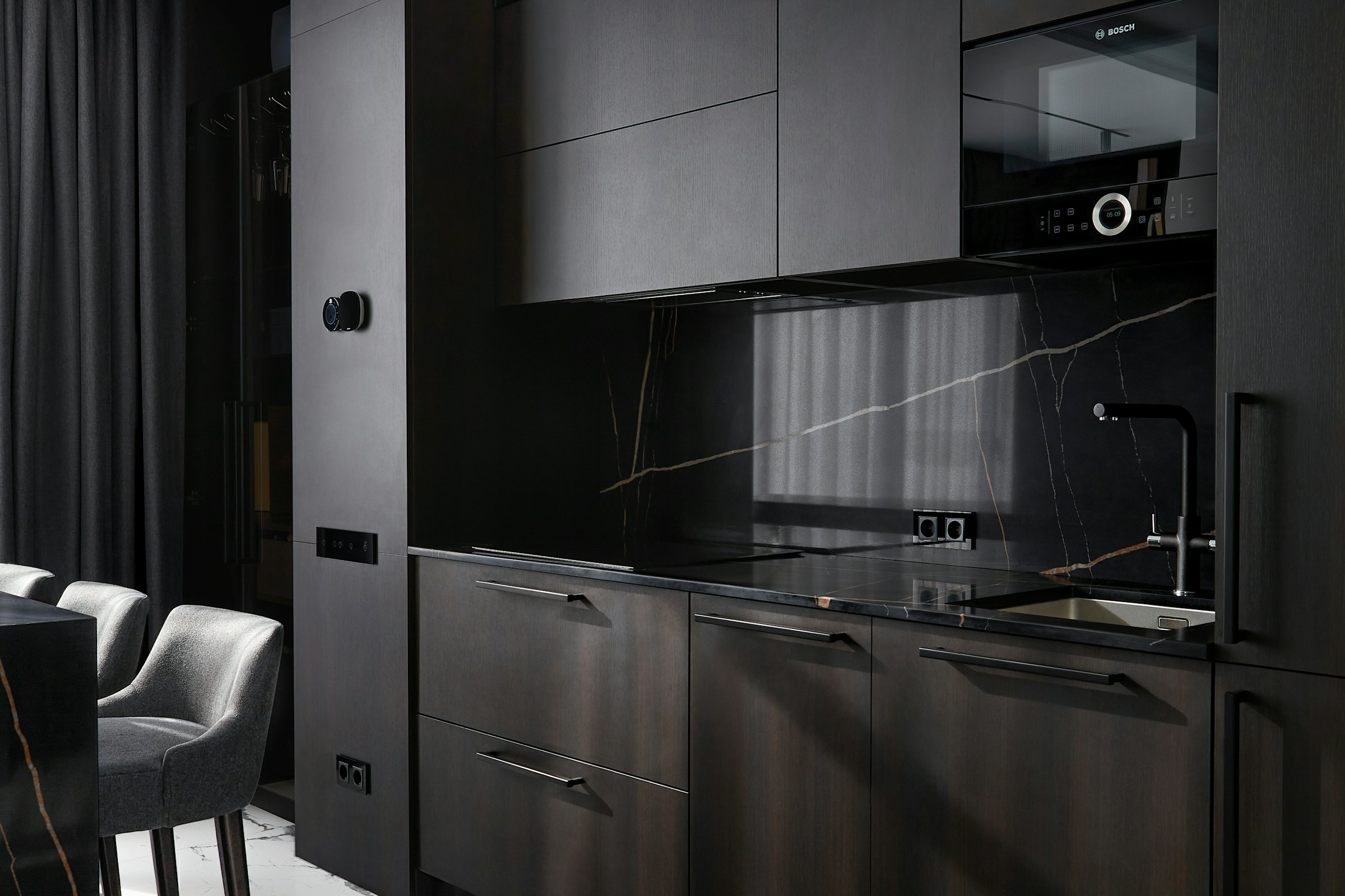 Cuisine contemporaine avec façades bois, éléments anthracite et îlot central en pierre sombre